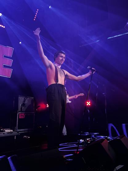 Vocalist with arms wide looking at audience with a smile, shades still off