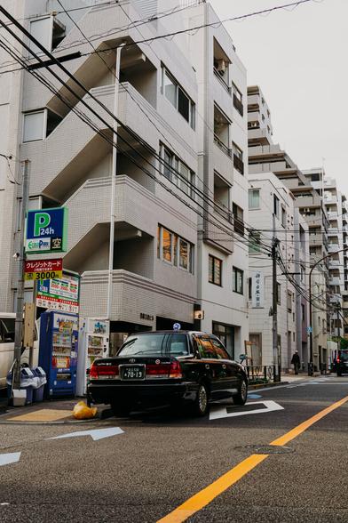 photo of a traditional Tokyo taxi parking at the side of a side street, it's a clear sunny day
