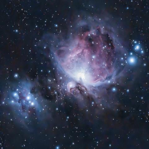Glowing red and blueish-white gaseous clouds sit in space with bright, young stars around them.