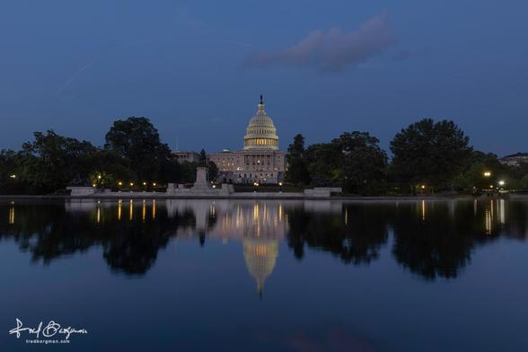 Capitol building in Washington DC lit up at night and reflecting into a body of water