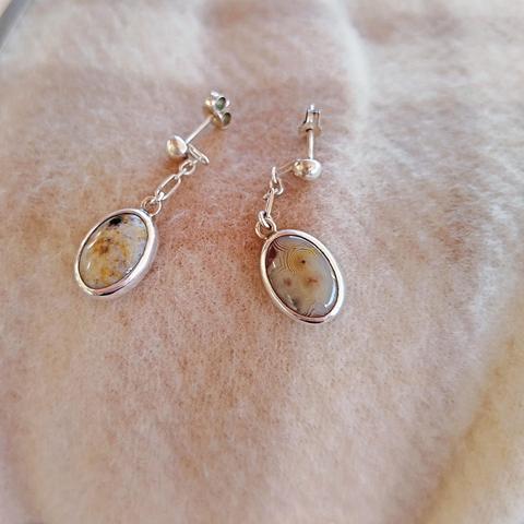 a pair of silver earrings with oval gemstones.