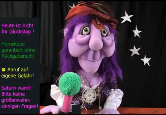 Hinter dem Mikrofon sitzt die Klappmaulpuppe Anastasia, die eine Wahrsagerin darstellt. Neben ihr werden einige Orakelsprüche eingeblendet, wie "Horoskope garantiert ohne Rückgaberecht" oder "Saturn warnt! Bitte keine größenwahnsinnigen Fragen!