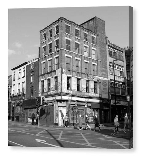 Black and white square photograph of a run down building in Manchester, England.  The building is Rambo's tattoo parlour.  The image is shown printed upon a box canvas.