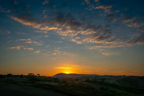 sunset over montejunto in portugal with wispy clouds lit by the setting sun
