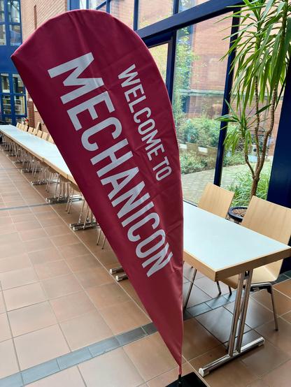 Ein roter Bannerständer mit weißer Schrift - Text: Welcome to Mechanicon