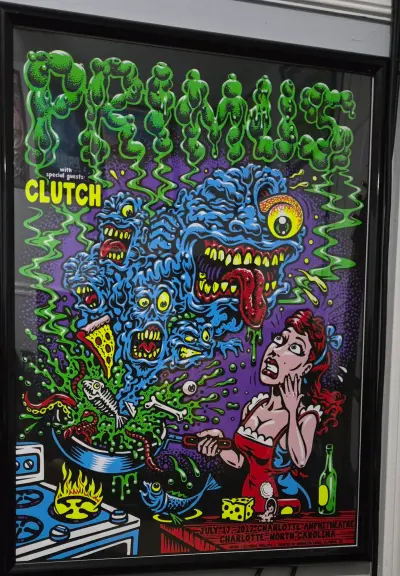 A psychedelic-style concert poster for the band Clutch, dated July 17, 2017, at the Charlotte Amphitheatre in Charlotte, North Carolina. The artwork is a chaotic, hand-drawn illustration with bold outlines and a limited color palette of purple, green, red, and black. A woman in a red dress, with a terrified expression, is facing a monstrous figure composed of eyes, teeth, and tentacles. The background is a swirling vortex of abstract shapes and disturbing imagery. The text 'Clutch' is prominently featured at the top, and the date/venue information is at the bottom.