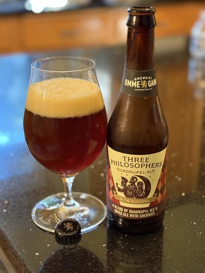 A snifter full of amber beer with a white bubbly head. The brown bottle has purple gold and brown checkered pattern and three wisemen highlighted by the moon.