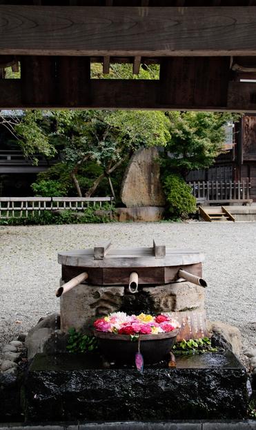 Cleansing water for your mouth and hands coming out of three spouts, falling into the basin below with colorful flowers floating