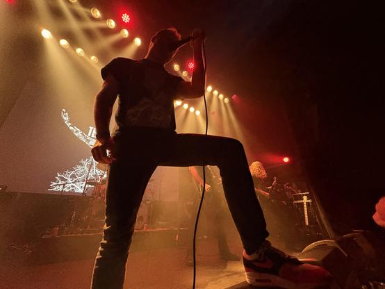 Joost Vervoort of Terzij De Horde on stage at Soulcrusher, small stage, leg upon the PA, silhouetted by the stage light.