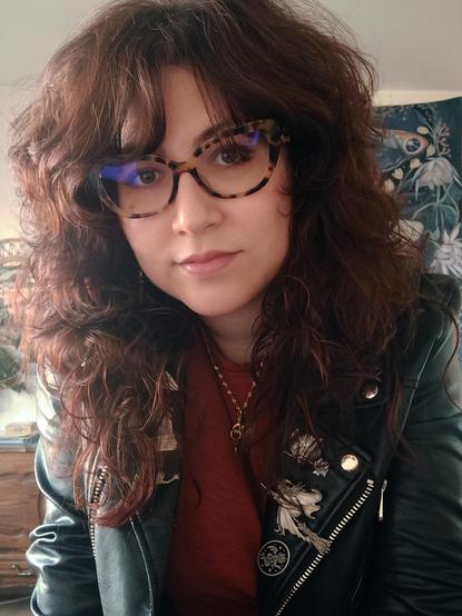 Self-portrait of a woman with long hair, wearing glasses and a leather jacket.