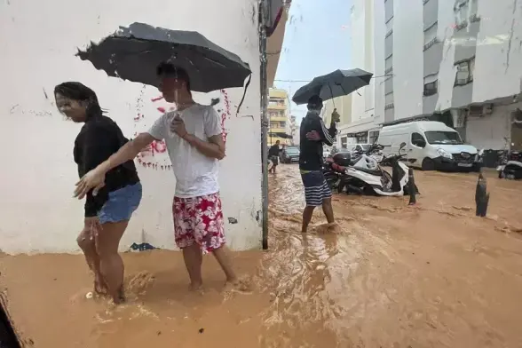 Überschwemmte strasse auf ibiza, Leute mit Regenschirm waren knöcheltief.