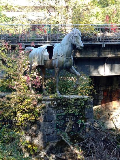 Sous un pont la statue d'un cheval. La selle est abîmée et laisse voir un trou béant dans la statue