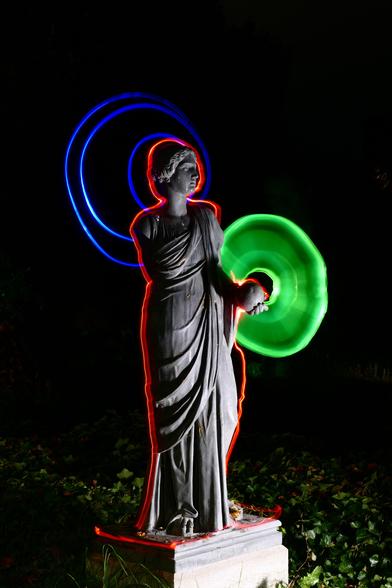 Die gleiche Statue wie im ersten Bild, diesmal mit konzentrischen Kreisen statt Quadraten und einem grünen Schild am linken Arm.