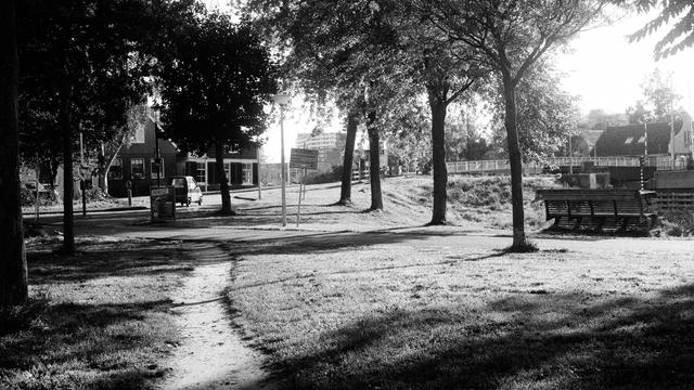 Black & white photo of the crossing of Noordhollandschkanaaldijk and Buiksloterdijk. Close by a small footpath, in the distance there is a Canta (tiny car common in Amsterdam Noord). The low morning light is nice and moody.