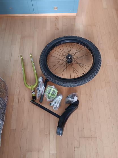 A unicycle in parts on a wooden floor.