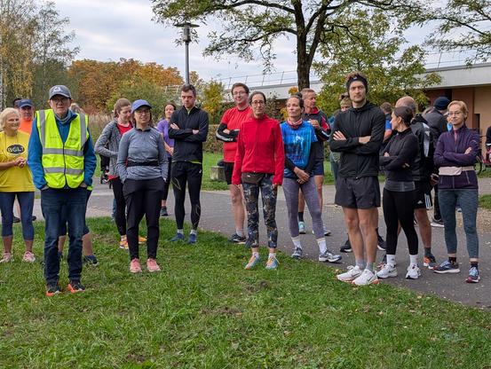 A group of runners listing to the briefing. In the background autumn leaves are visible.