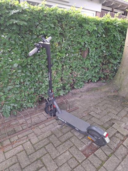 E-Roller steht vor grüner Hecke. Fahrzeug wurde in heute am Bahnhof in Delmenhorst geklaut. Kennzeichen ist 217 JCB. Aufkleber von Werder Bremen sind jeweils am Trittbrett auf beiden Seiten angebracht.