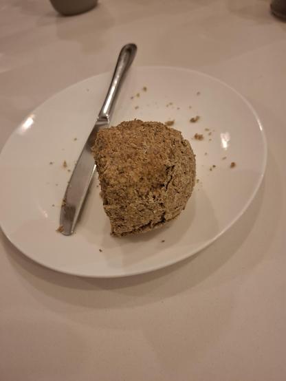 A quarter of the soda bread on a white plate with a knife.