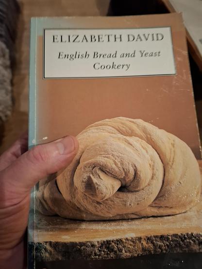 A photo of a book. Elizabeth David English Bread and Yeast Cookery. Picture of some dough on the front. Model's hand slightly visible.