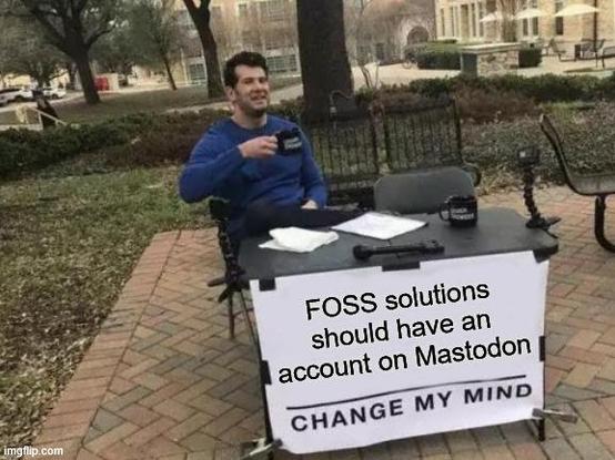 "Change my mind" meme of a guy sitting at a table with a banner that says "FOSS solutions should have an account on Mastodon - CHANGE MY MIND". He is wearing a blue shirt and drinking a cup of coffee.