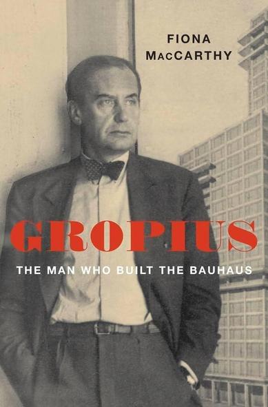 This is a book cover featuring a portrait of a person in a sepia tone. The person is depicted from the chest up, wearing a dark suit, a light-colored shirt, and a dark tie. The person is looking directly at the viewer with a serious expression. Large, bold red lettering is overlaid on the image, spelling out "GROPIUS". Below that, in smaller white lettering, is the text "THE MAN WHO BUILT THE BAUHAUS". At the very top of the cover is the name "FIONA MacCARTHY". In the background, slightly blurred, is a tall building with a grid-like pattern of windows.

Provided by @altbot, generated privately and locally using Gemma3:27b