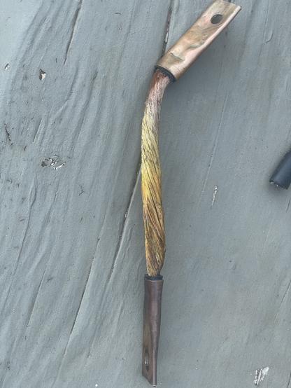 a 10" length of 1/0 copper stranded welding wire with copper lugs crimped on the ends.  the insulation has been cut off.  the bottom 2/3 of the stranded wire shows discoloration, as does the lower copper lug