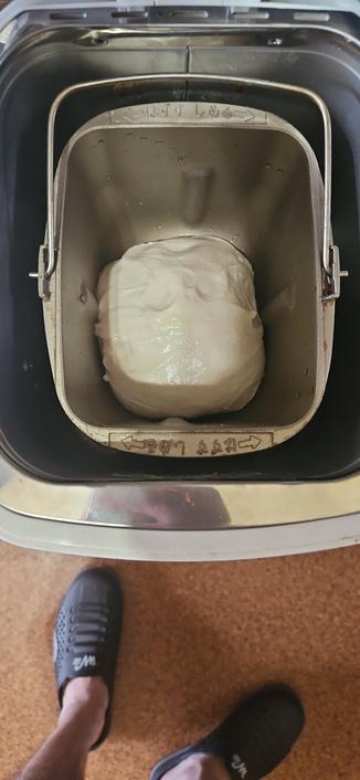 a photo of a happy little ball of dough sitting snuggly in a bread maker. also my feet are in frame.
