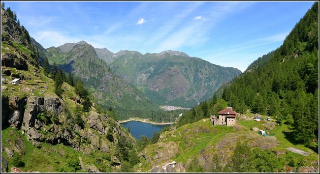 Un lac encaissé dans un petit vallon montagneux.
Quelques maisons sur la droite.