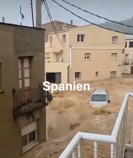 Straße in Spanien unter Wasser, die Flut reißt ein Auto mit.