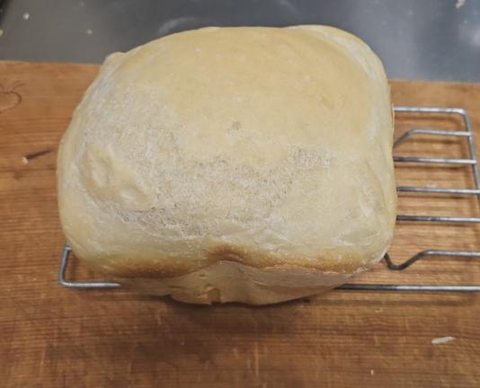a photo of a freshly baked loaf of bread. the top is golden, and the side is browned slightly.