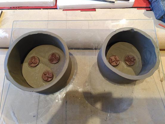 5 petits médaillons en argile crue de la taille d'une pièce de 50 centimes d'euro sont placés dans des boîtes rondes en argile crue aussi qui vont servir de barrière pour couler du plâtre et faire des moules. Les médaillons sont sculptés en triskell ou en hermine de différents styles.