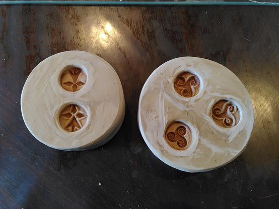 2 moules en plâtre circulaires. L'un contient 2 médaillons d'hermine et l'autre 3 médaillons de triskell. Tous dans des styles différents. Les originaux ayant été sculptés a la main. Chaque médaillon fait la taille d'une pièce de 50 centimes d'euros.