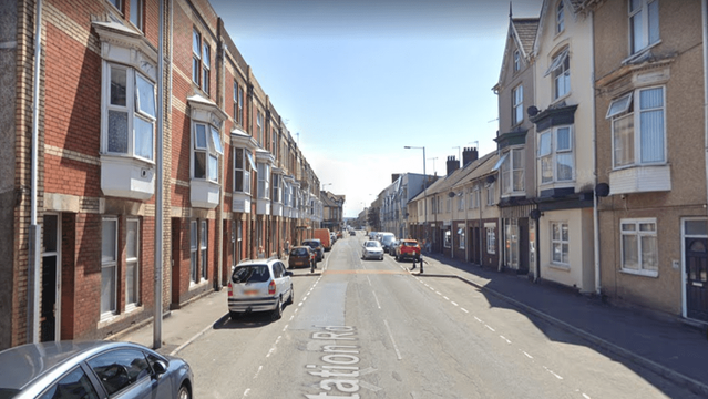 Street view of Station Road in Llanelli showing terraced houses and HMOs on both sides of the road near the train station.