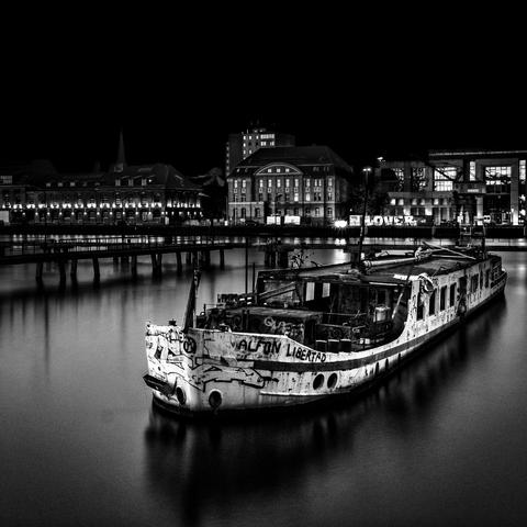 Schwarz Weiss Aufnahme eines alten Schiffes im Westhafen in Berlin bei Nacht
