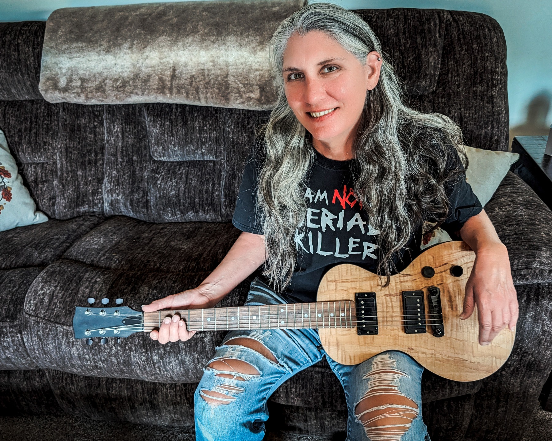 Krissy on the living room couch, with guitar, looking up at me as I take her photo