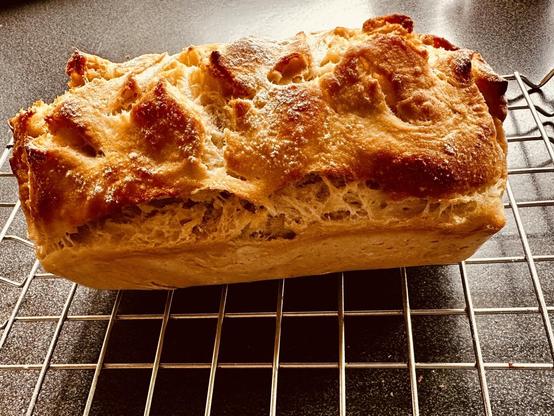 A freshly baked loaf of bread rests on a cooling rack.