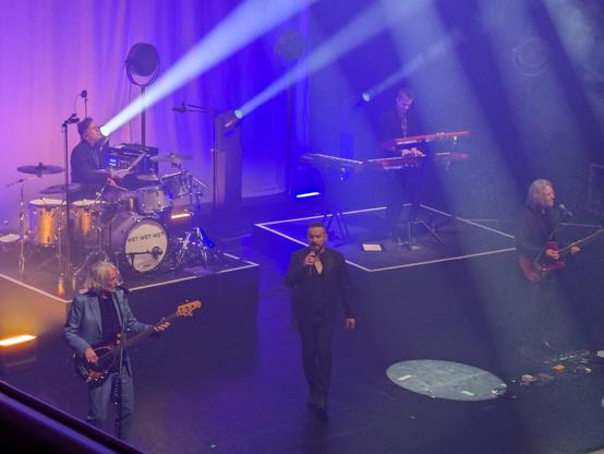 2 guitar players, a drummer, keyboard and lead singer on the stage