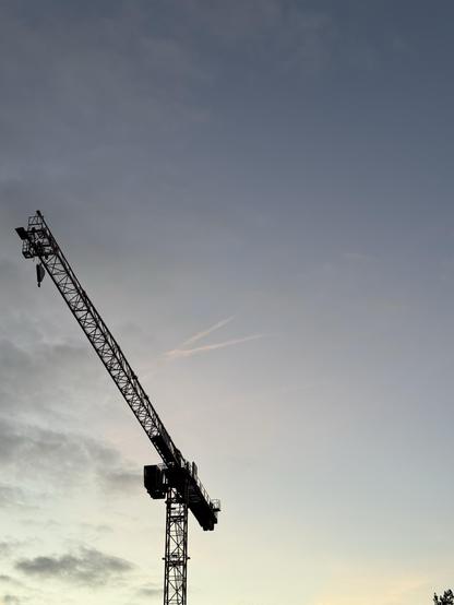 Ein Kran zeichnet sich schwarz vor einem fahl blauen Abendhimmel ab
