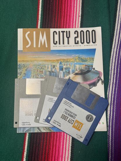 The SIM CITY 2000 BigBox. On top of it are the 3.5" floppy disks for the game and add-on.