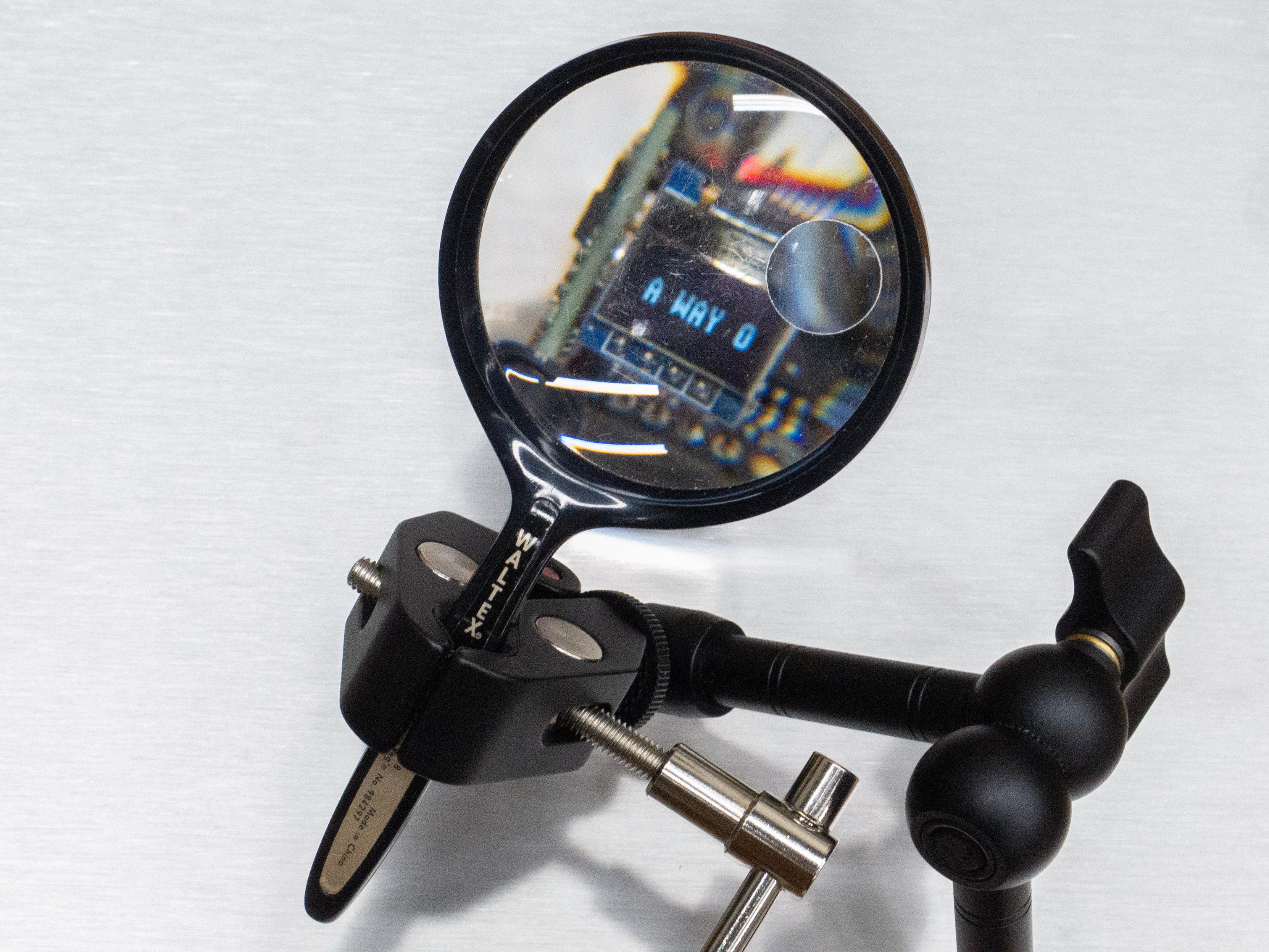 A more direct view through the magnifying glass shows the chunky pixels more clearly, currently reading, "A WAY OF..."