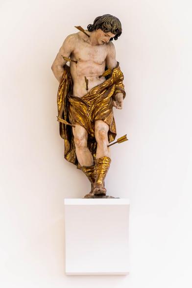 🇫🇷 Statue en bois polychrome de Saint Sébastien dans l’église Saint Moritz d’Augsbourg. Le saint, transpercé de flèches, est vêtu d’un drapé doré et se détache sur un fond blanc lumineux, exprimant à la fois la douleur et la sérénité.
🇬🇧 Polychrome wooden statue of Saint Sebastian in St. Moritz Church, Augsburg. The saint, pierced by arrows and wrapped in golden drapery, stands out against a bright white background, conveying both suffering and serenity.