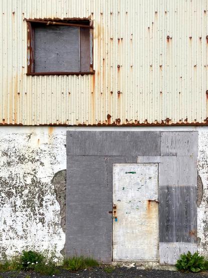 An ugly white door on a run down building.