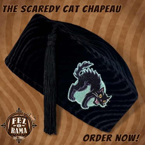 Black velvet tasseled cap with an embroidery featuring a hissing black cat with an arched back in front of a pale green full moon.