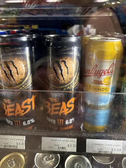 A shelf of drinks at Sheetz featuring cans of a Monster Energy-branded alcoholic beverage called The Beast with packaging evocative of Beast Wars, complete with an orange logo in a Beast-adjacent font and a big scaly eye with a Monster m in the middle.