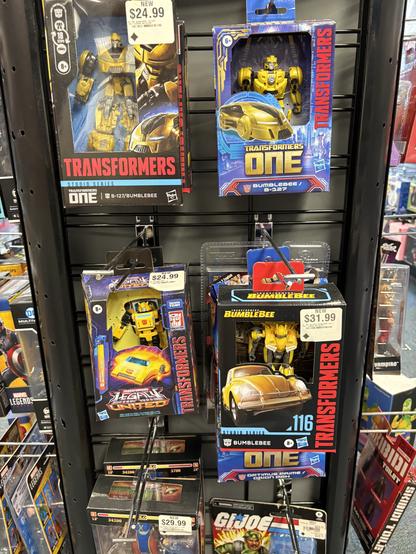A hanging display at a GameStop with four completely different figures of Bumblebee from Transformers.