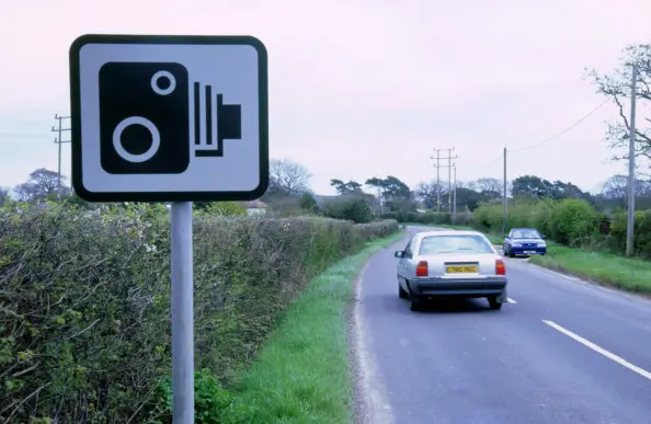 a picture of a UK speed camera warning sign. it's an iconised representation of a 19th century era camera, with the bellows and everything