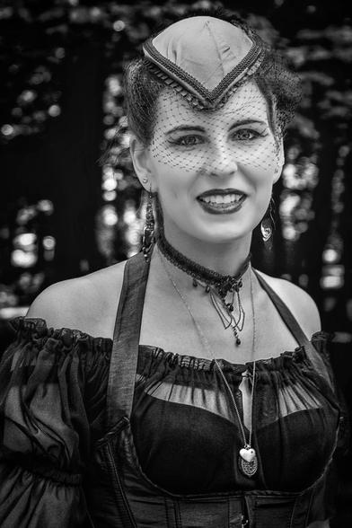 Schwarz Weiss Portrait einer jungen Frau mit einem Hut, an dem ein Netzartiger Schleier befestigt ist