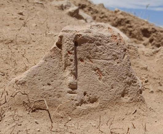 Ritrovamento di un oggetto in pietra nella regione di Argištiḫinili, Armenia, con una superficie irregolare e segni di erosione, circondato da terreno secco.