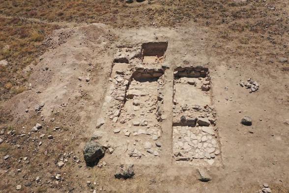 Veduta aerea di scavi archeologici che mostrano due aree rettangolari con pietre esposte e terreno arido, situate in un contesto archeologico di Argiștiḫinili, in Armenia.