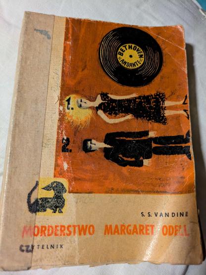 Zdjęcie książki "Morderstwo Margaret Odell" autorstwa S.S. Van Dine'a. Książka jest zniszczona, utrzymana w jasnych barwach, w serii z jamnikiem i przedstawia dwie namalowane leżące postacie oraz płytę gramofonową.
